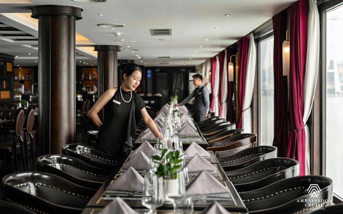 Dining setup on Ha Long Bay 5-Star Ambassador Cruise with staff preparing tables.