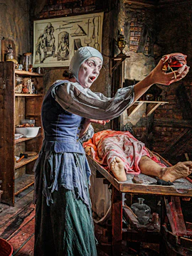 Man in medieval torture chamber with tools at London Dungeon.