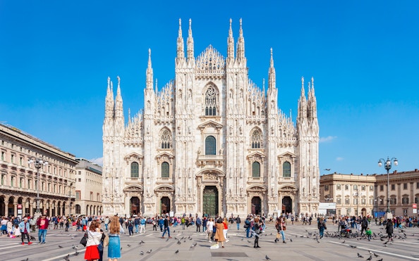 Crowd in front of Milan's Duomo Cathedral on a sunny day.