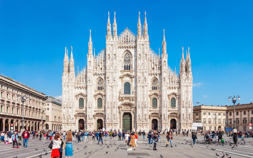 Crowd in front of Milan's Duomo Cathedral on a sunny day.