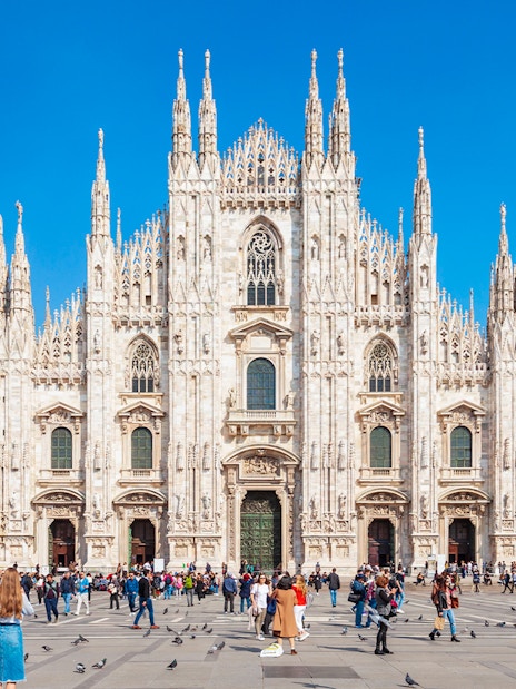 Crowd in front of Milan's Duomo Cathedral on a sunny day.