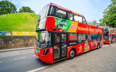 Oxford sightseeing bus passing historic building.