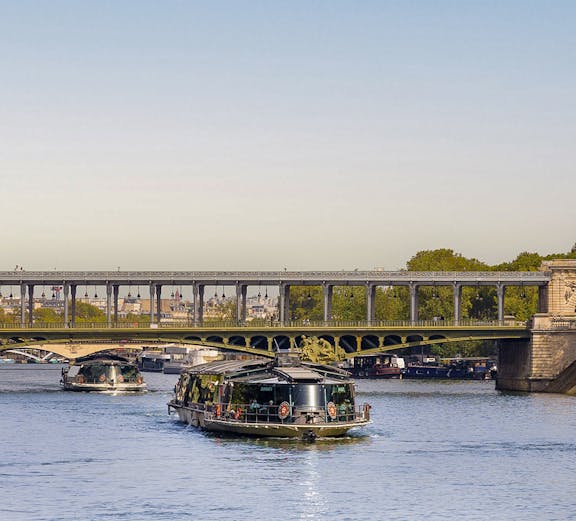 Seine River cruise boats passing under a bridge in Paris, France.