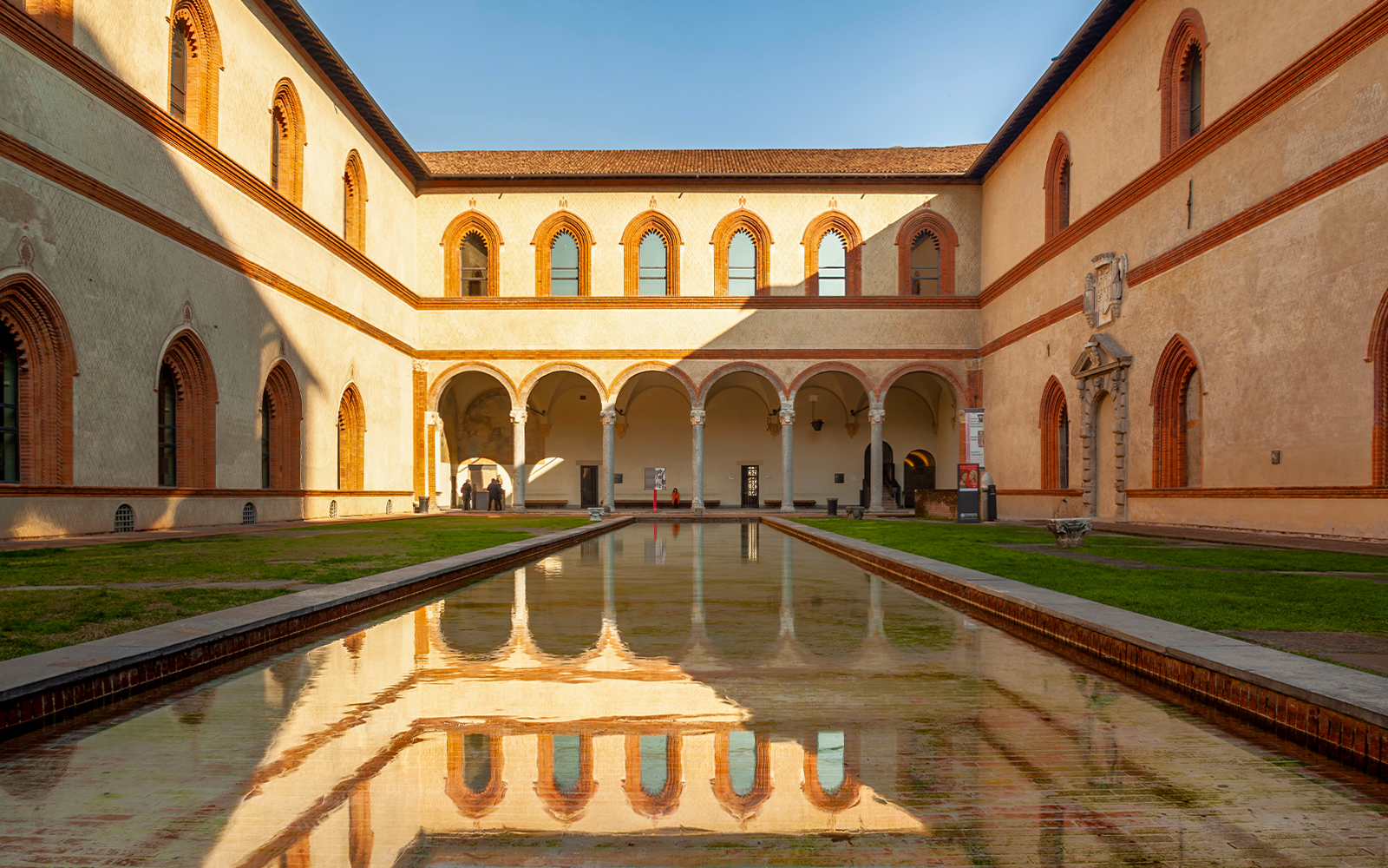 Sforza Castle courtyard with arched walkways and reflective pool, Milan, Italy.