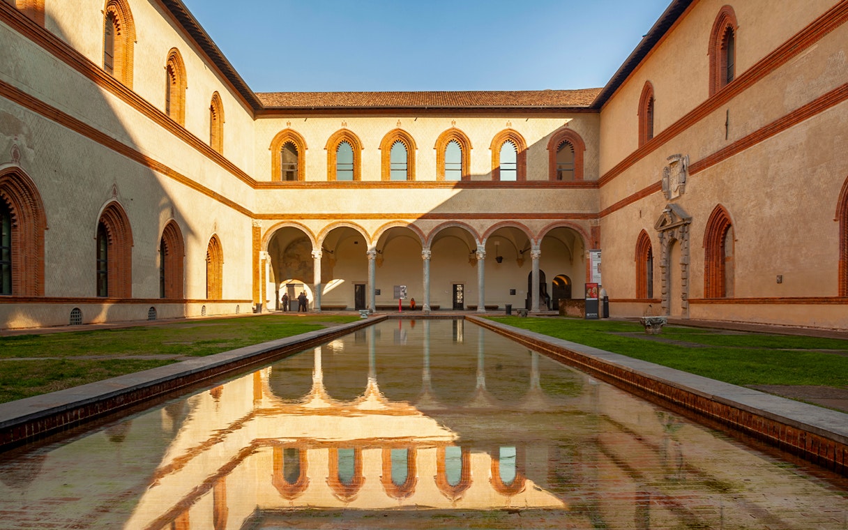 Sforza Castle courtyard with arched walkways and reflective pool, Milan, Italy.