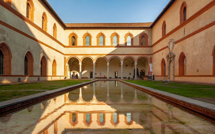 Sforza Castle courtyard with arched walkways and reflective pool, Milan, Italy.