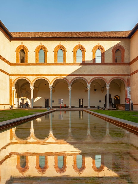 Sforza Castle courtyard with arched walkways and reflective pool, Milan, Italy.