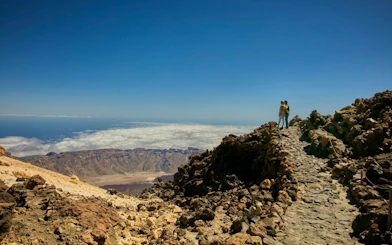 Guests on Mount Teide summit path with views of volcanic landscape and clouds.