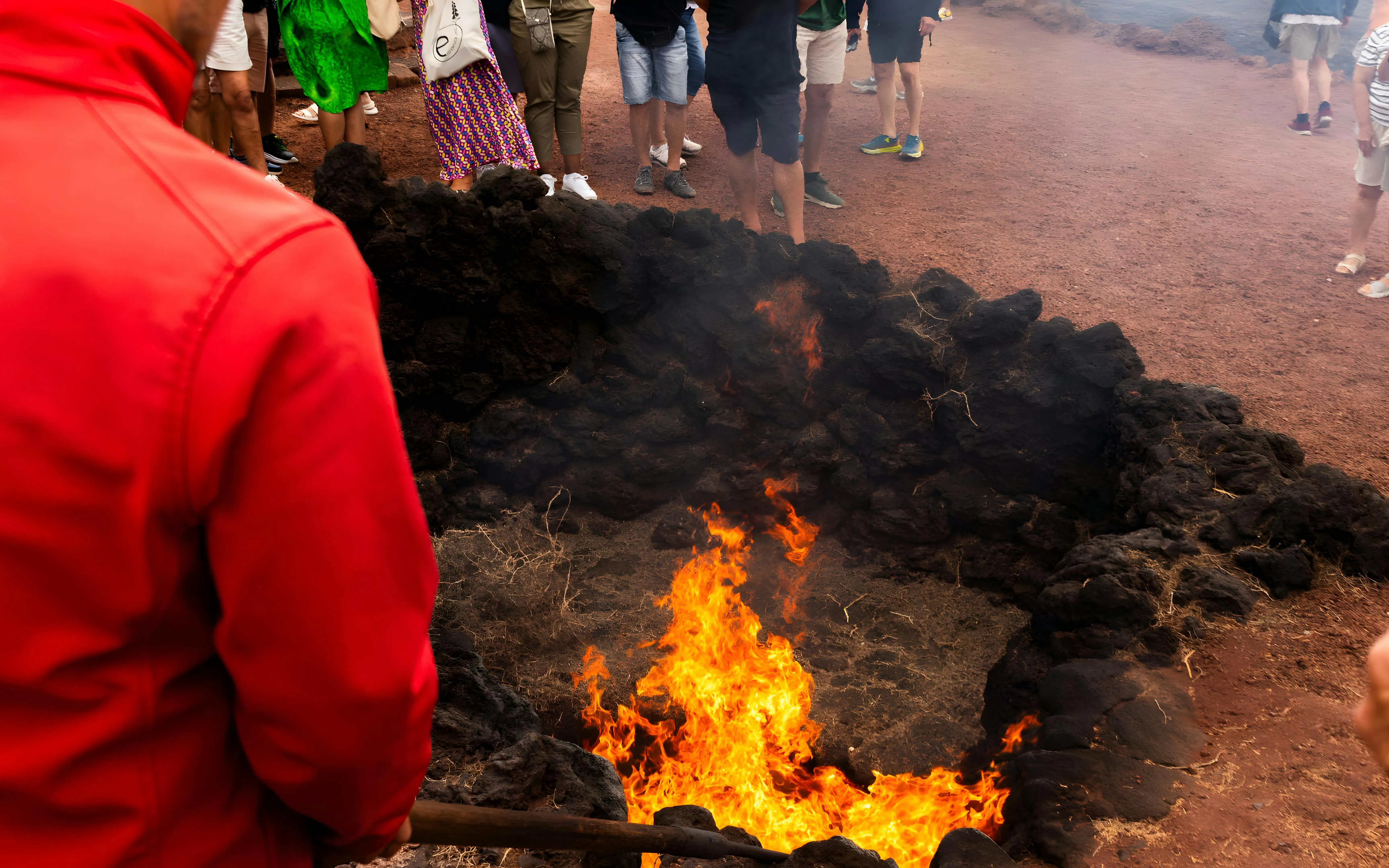 Timanfaya National Park fire demonstration with flames emerging from volcanic rocks.
