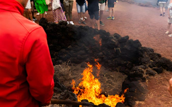 Timanfaya National Park fire demonstration with flames emerging from volcanic rocks.