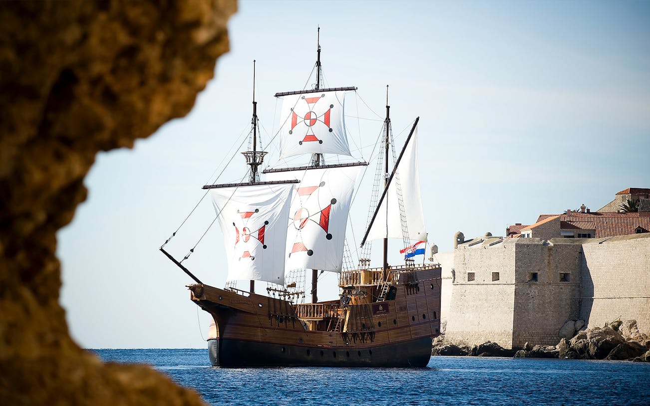 Historic ship sailing near Dubrovnik city walls on Panoramic Cruise and Walking Tour.