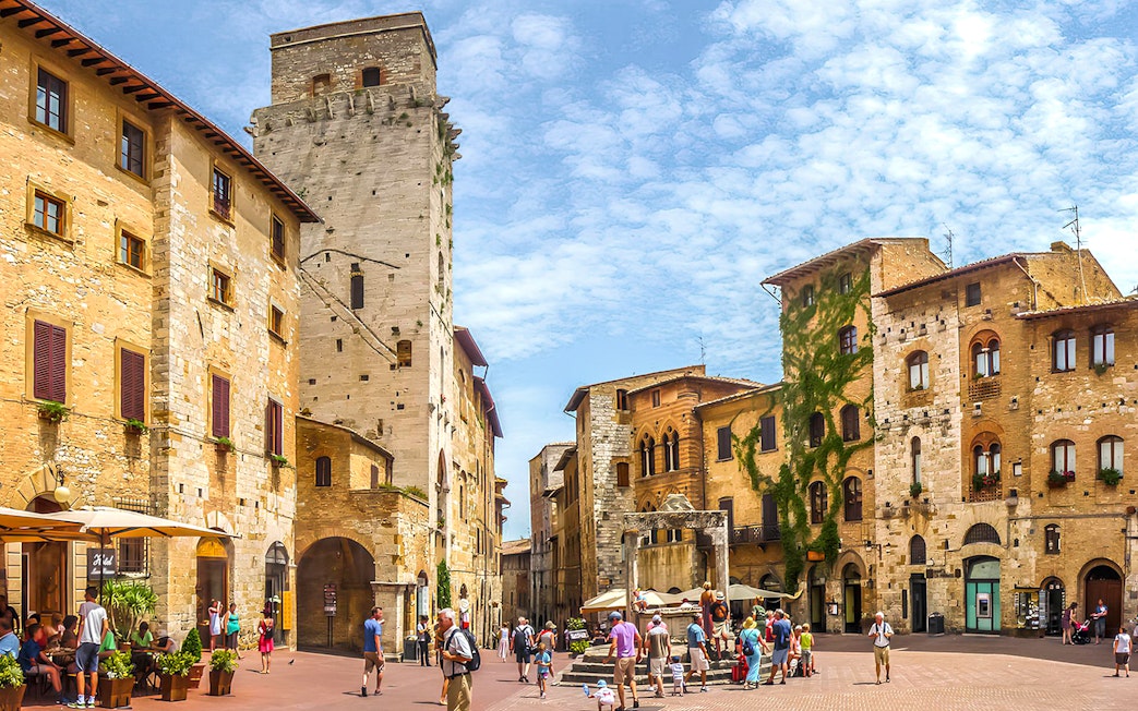 Streets of San Gimignano with historic stone buildings and tourists exploring.