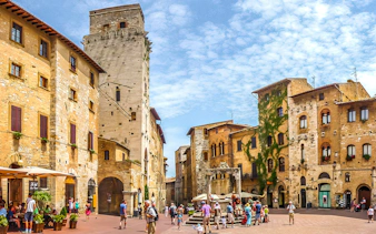 Streets of San Gimignano with historic stone buildings and tourists exploring.