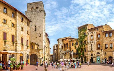 Streets of San Gimignano with historic stone buildings and tourists exploring.