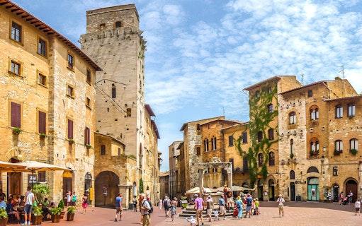 Streets of San Gimignano with historic stone buildings and tourists exploring.