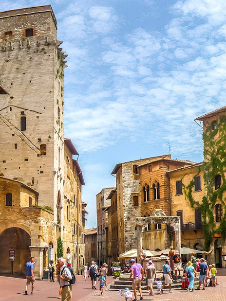 Streets of San Gimignano with historic stone buildings and tourists exploring.