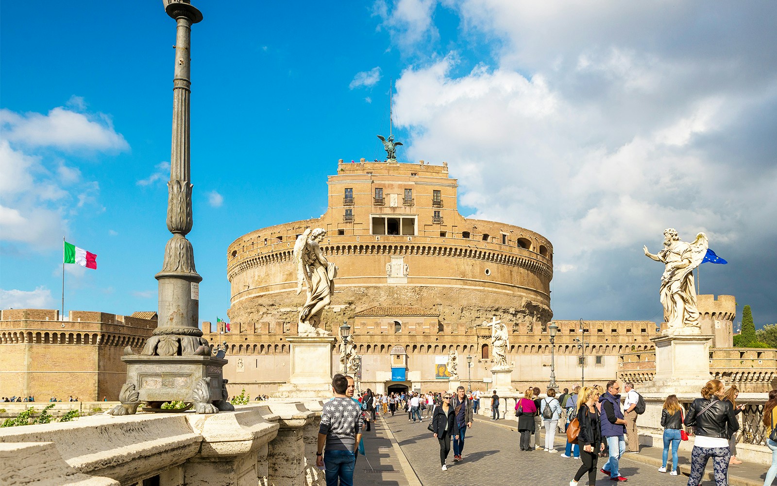Castel Sant'Angelo in Rome with tourists on the bridge and statues in view.