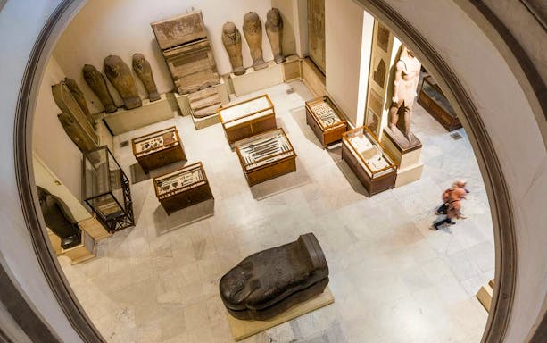 Museum exhibit with ancient Egyptian artifacts and sarcophagi in Cairo.
