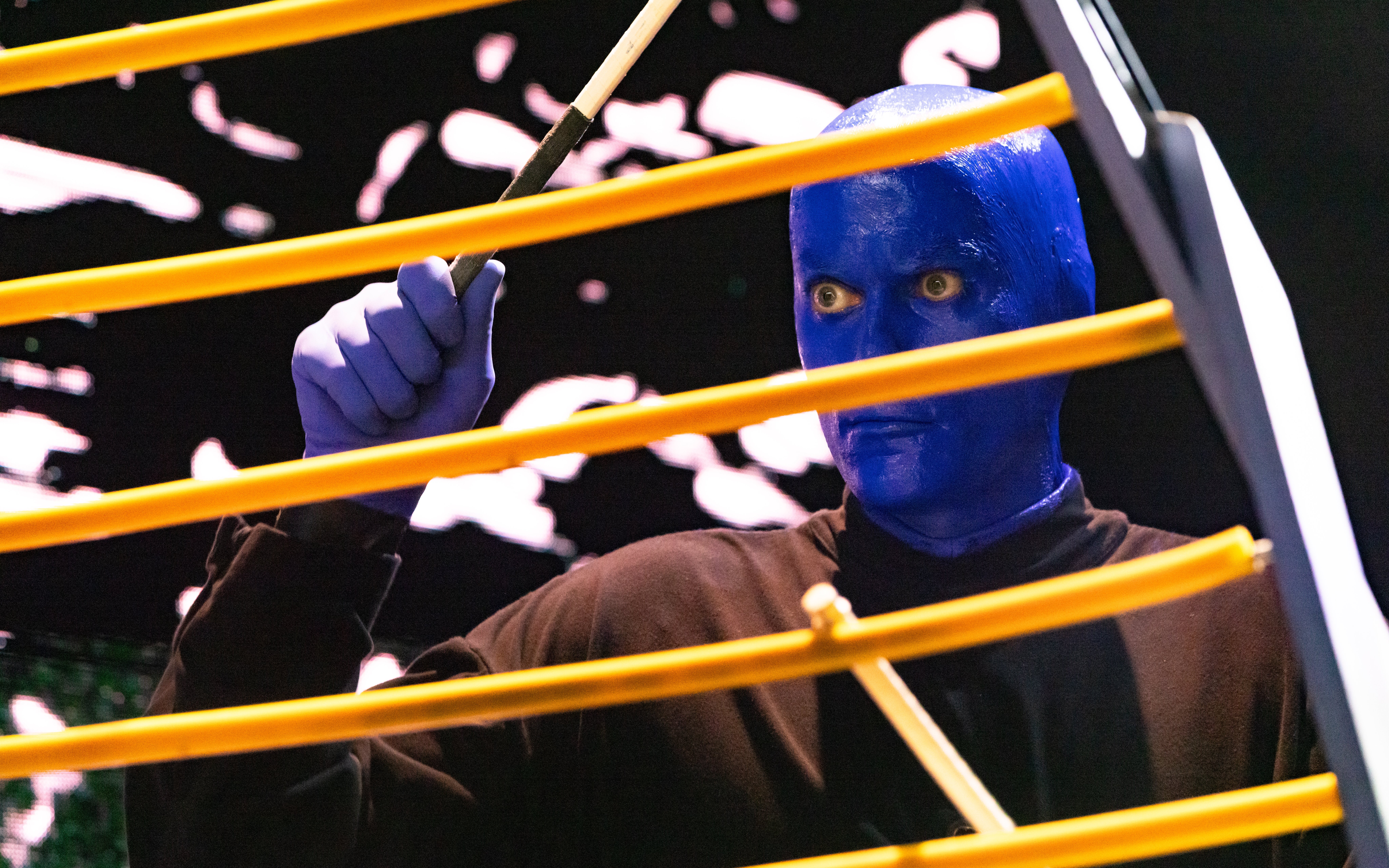Blue Man Group performer playing percussion instrument on stage, Orlando.