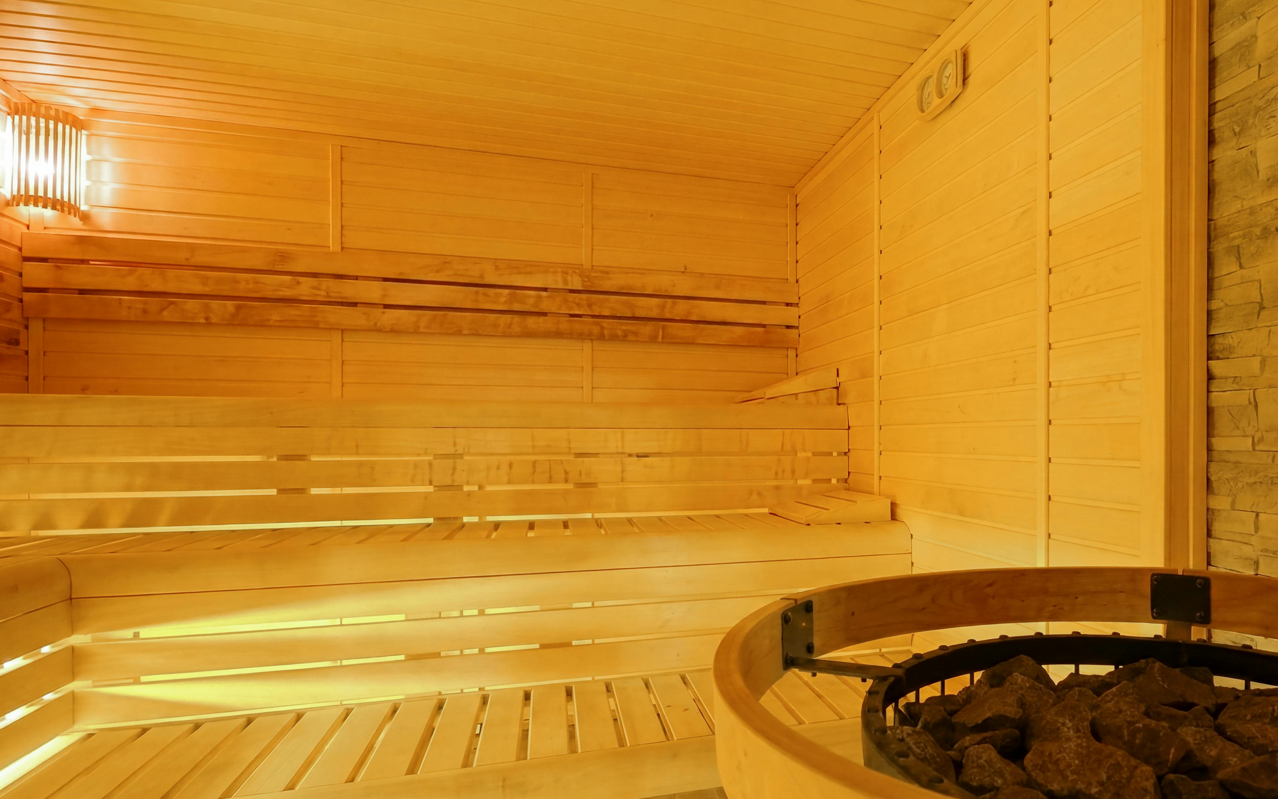 Wooden sauna interior at Dandar Spa with seating and heater.