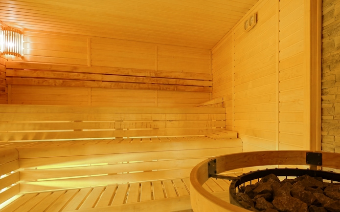 Wooden sauna interior at Dandar Spa with seating and heater.