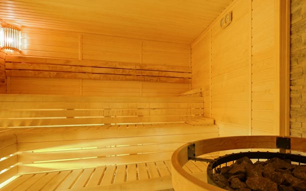 Wooden sauna interior at Dandar Spa with seating and heater.
