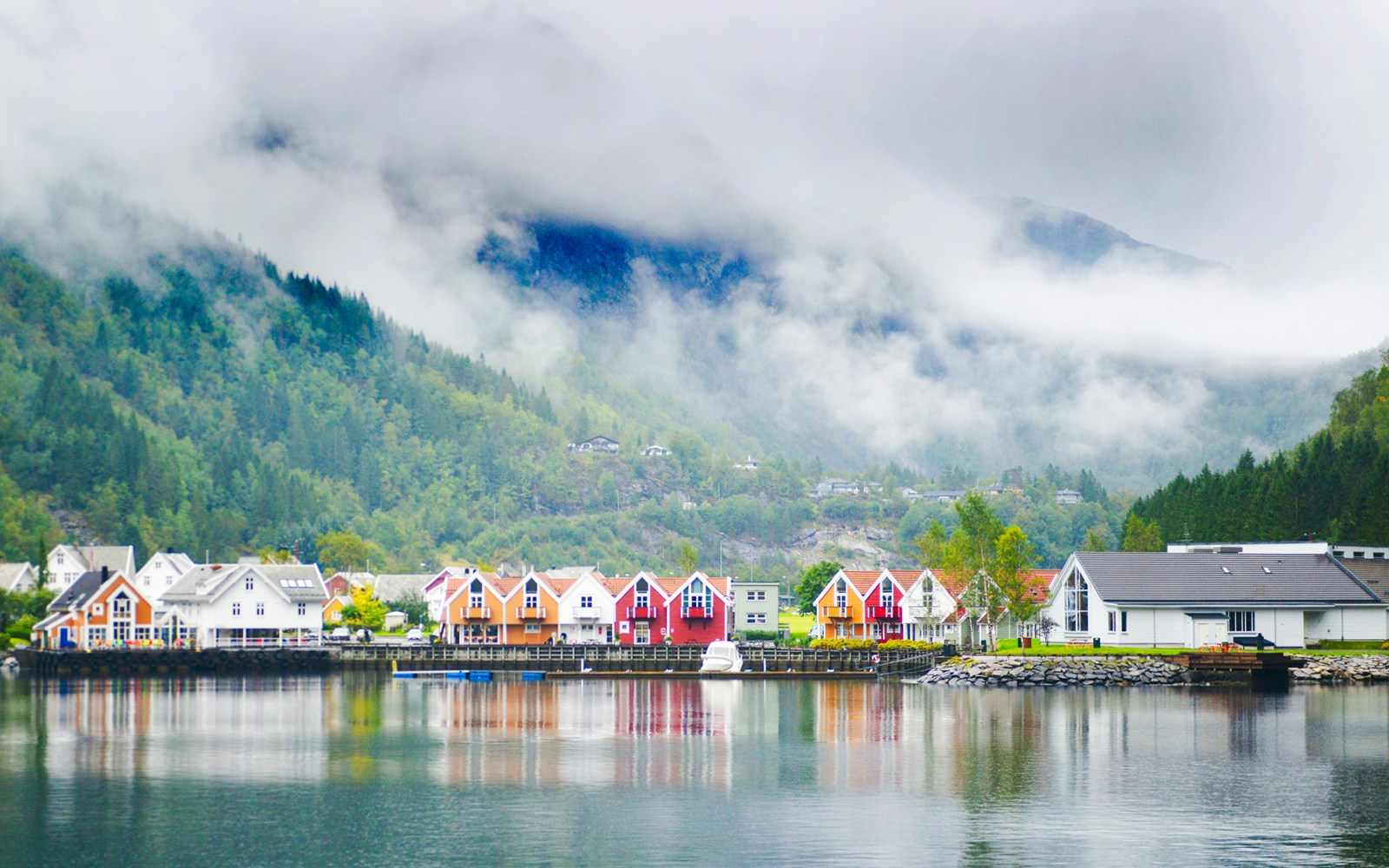 Boat cruising through Mostraumen fjord with steep cliffs and lush greenery in Norway.