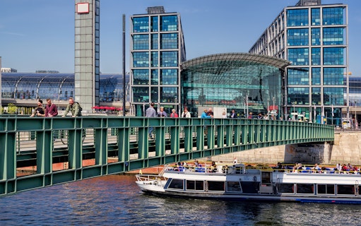 Berlin river cruise boat passing by Hauptbahnhof station with passengers on board.