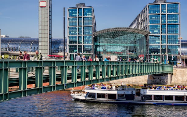 Berlin river cruise boat passing by Hauptbahnhof station with passengers on board.