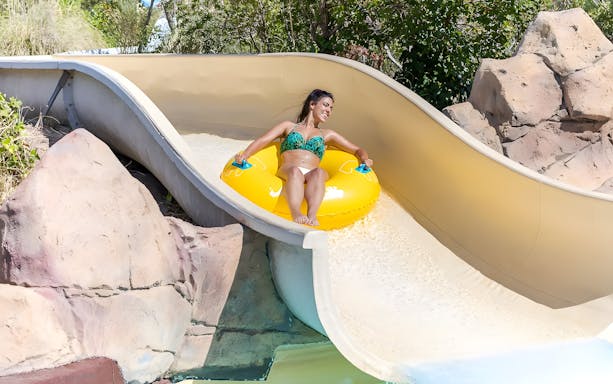 Person enjoying Rio Bravo slide at Aquopolis Villanueva de la Cañada on a yellow inflatable.
