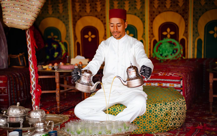 Man pouring tea during hot air balloon tour in Marrakech.