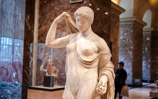 Tourists viewing a classical statue inside the Louvre Museum, France.