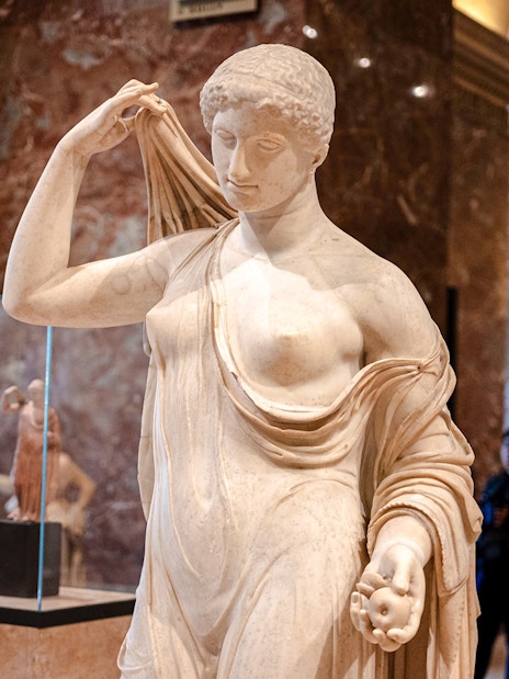 Tourists viewing a classical statue inside the Louvre Museum, France.