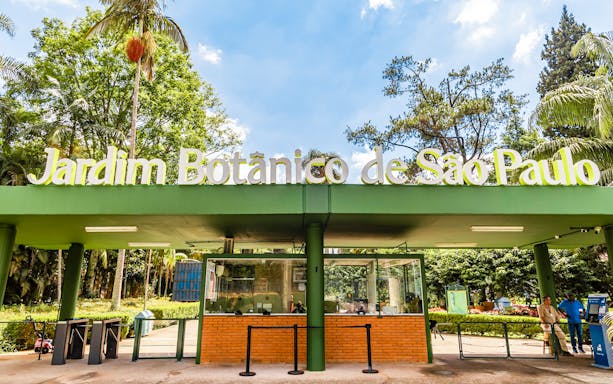 Entrance of Jardim Botânico de São Paulo with greenery and ticket booth.