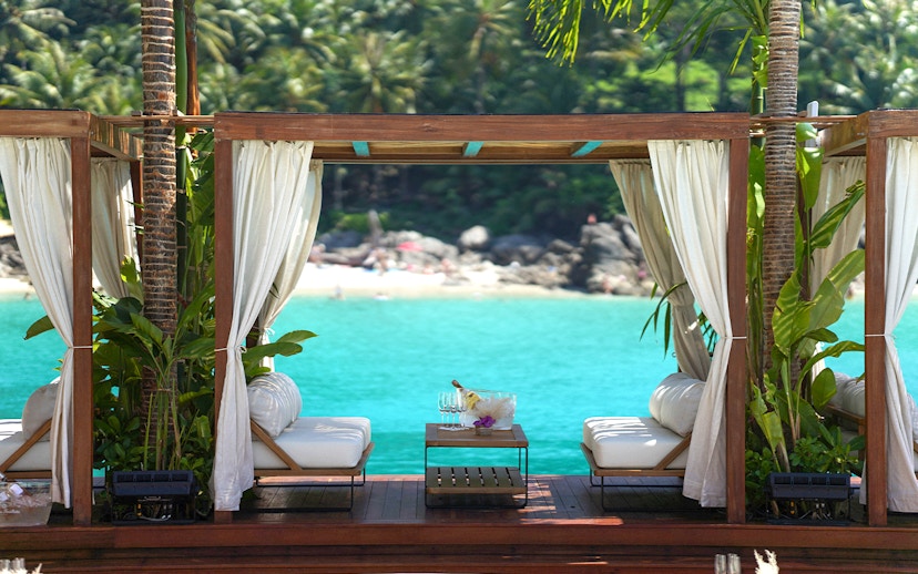 Private cabana at Yona Beach Club, Phuket, overlooking turquoise water and lush greenery.