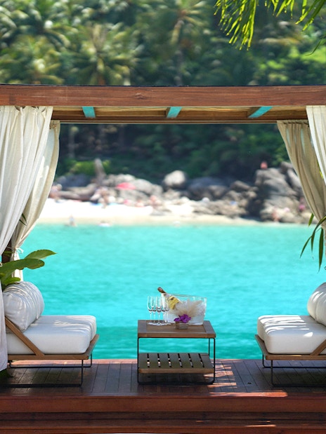 Private cabana at Yona Beach Club, Phuket, overlooking turquoise water and lush greenery.