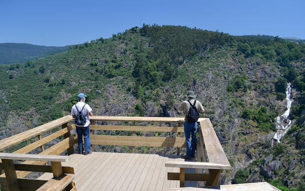 Visitors on a viewing platform overlooking the Paiva Walkways and waterfall in Arouca, Portugal.