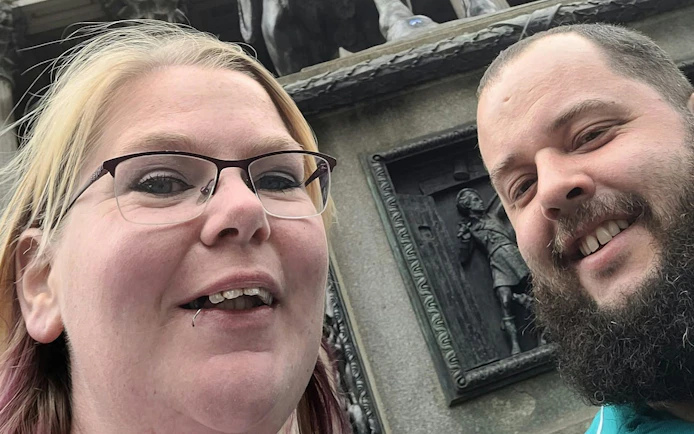 Two people smiling in front of the Duke of Wellington statue in Glasgow.