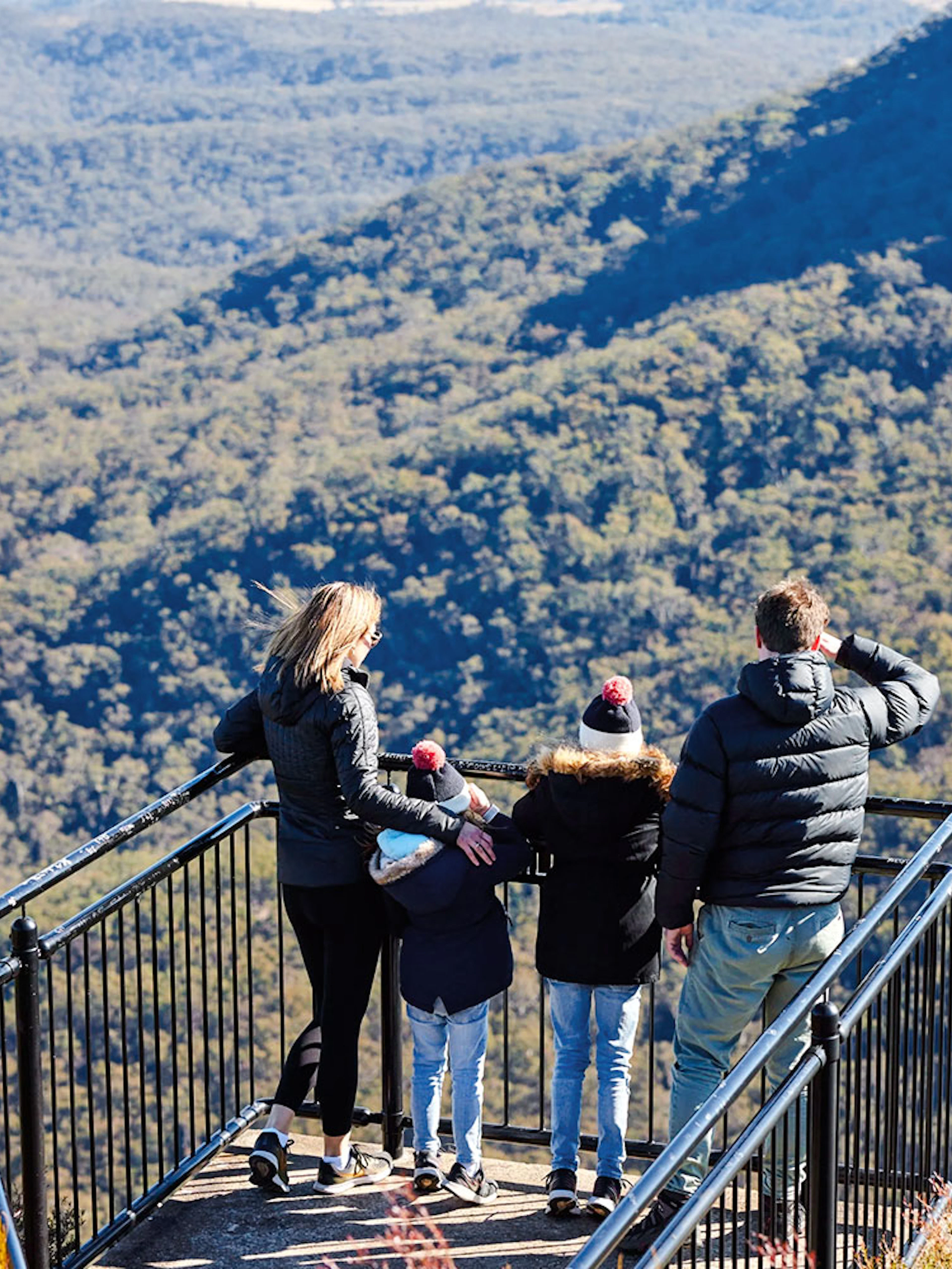 Family at lookout point in Blue Mountains National Park, viewing expansive forest landscape.