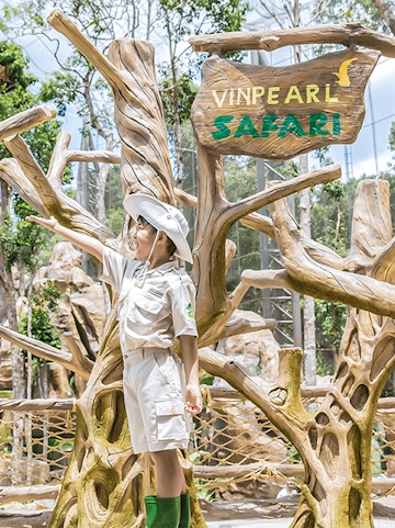 Child in safari outfit at Vinpearl Safari entrance sign.