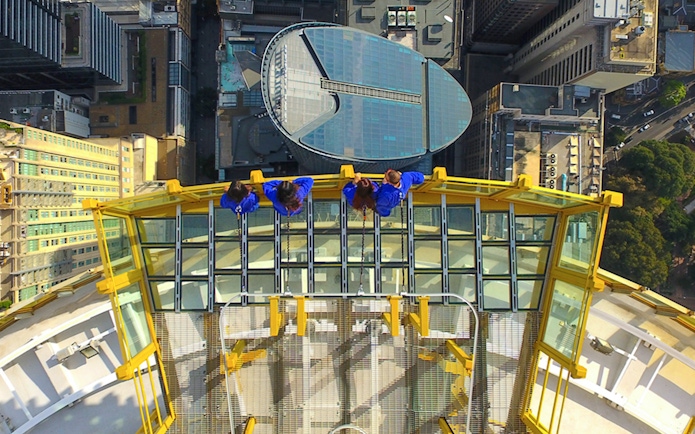 Visitors on Skywalk at Sydney Tower Eye overlooking cityscape.
