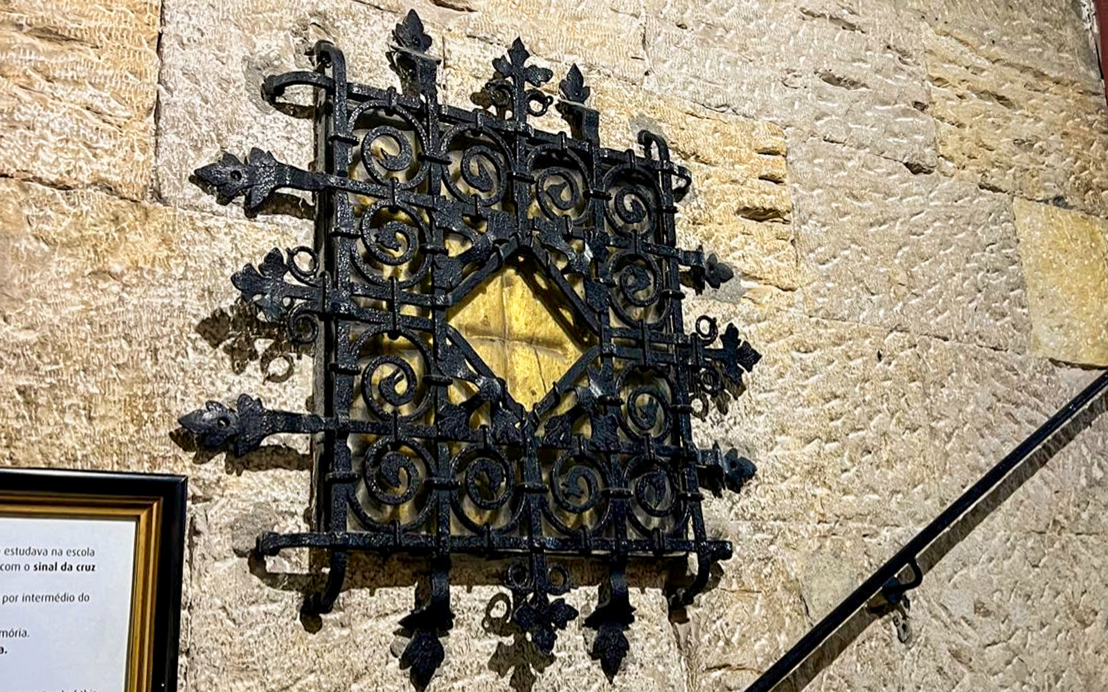 Ornate black iron grille on stone wall, part of treasury collection.