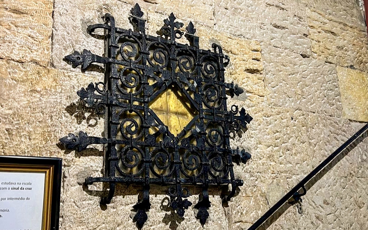 Ornate black iron grille on stone wall, part of treasury collection.