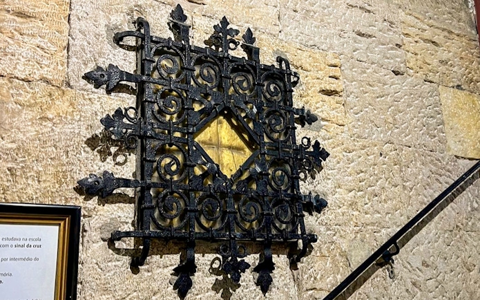 Ornate black iron grille on stone wall, part of treasury collection.