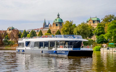 Sightseeing boat on Vltava River with historic Prague architecture in the background.