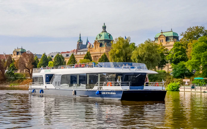 Sightseeing boat on Vltava River with historic Prague architecture in the background.