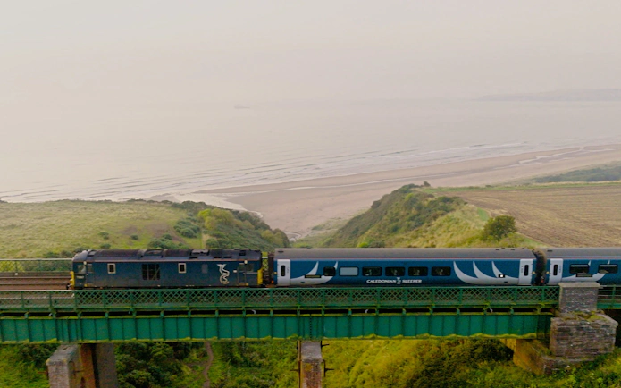 Train crossing a coastal bridge in Europe with ocean view.