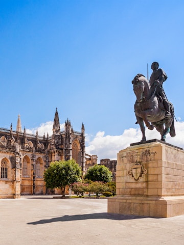 Equestrian statue near Batalha Monastery, Portugal, with Gothic architecture in the background.