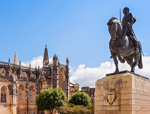 Equestrian statue near Batalha Monastery, Portugal, with Gothic architecture in the background.