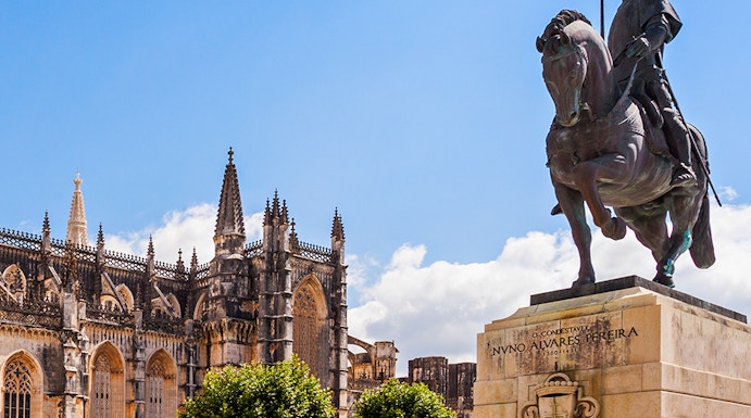 Equestrian statue near Batalha Monastery, Portugal, with Gothic architecture in the background.